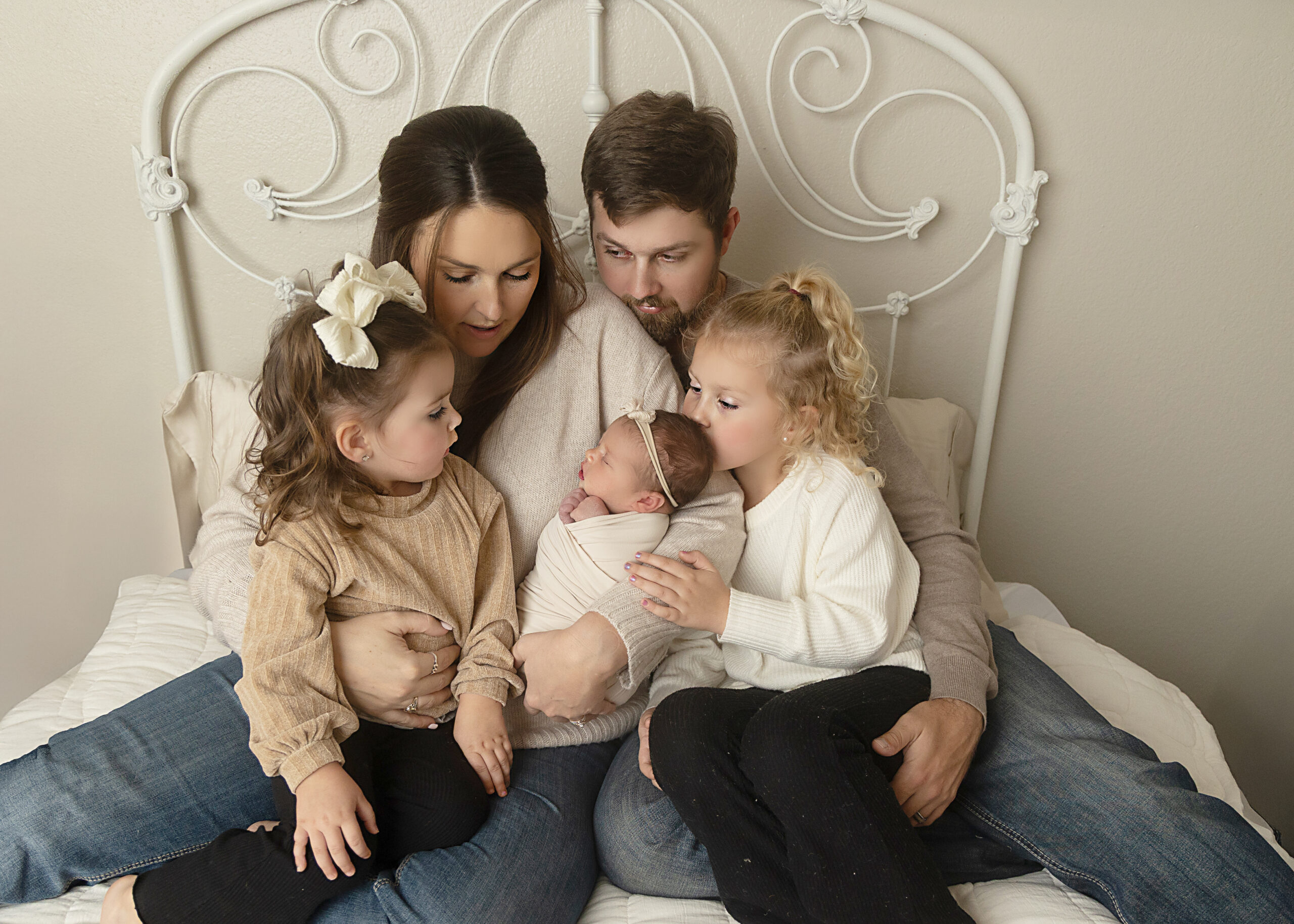 mom dad baby siblings on bed for newborn photography